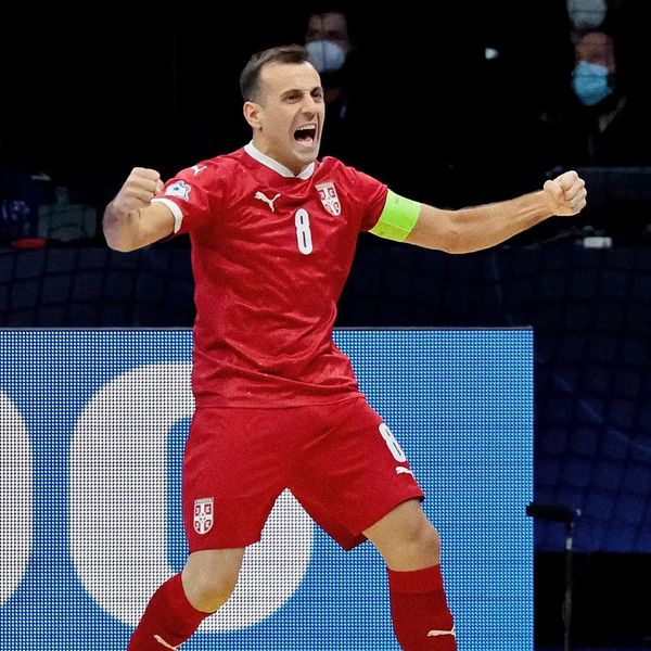 Serbian futsal player celebrates a goal passionately in a red uniform.
