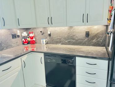 Modern kitchen corner with white cabinets and black dishwasher.