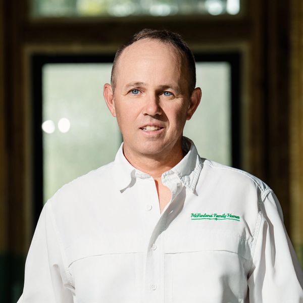 Man in white shirt with company logo posing indoors.