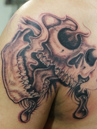 Black and grey tattoo skull on the upper right chest.