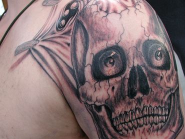 Black and grey skull tattoo on a shoulder.