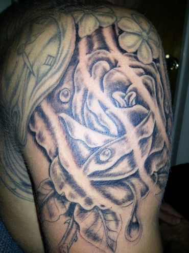 Black and grey rose tattoo as part of a sleeve on an upper arm.