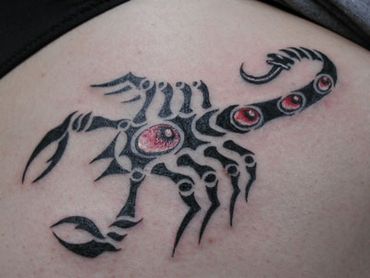 Tribal scorpion tattoo with red jewels on it's back. 