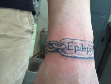 Lettering tattoo of epilepsy bracelet.