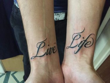 Script lettering tattoo on both wrists.