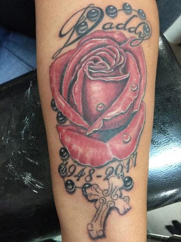 Memorial color red tattoo with name on a lower inner arm.