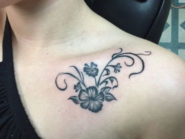 Black and grey flower tattoo on a woman upper left chest.