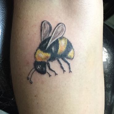 Color bee tattoo on an arm.