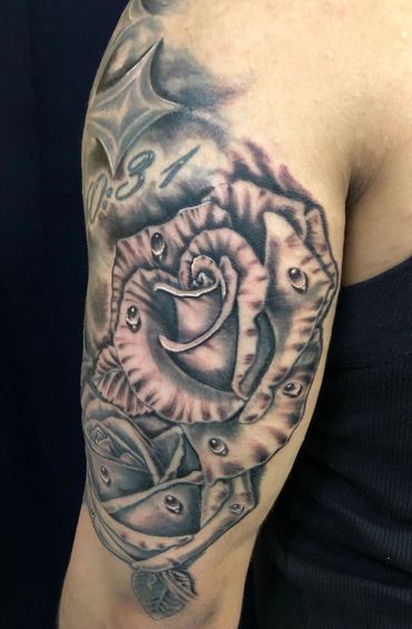 Black and grey tattoo of rose on arm.
