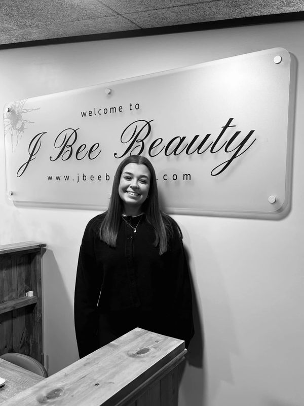 Woman smiling in front of J Bee Beauty sign.
