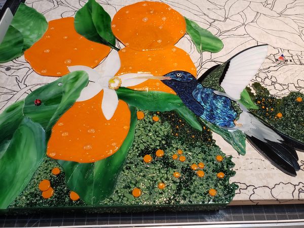 Stained glass artwork mosaic low relief hummingbird and tangerines by glass artist Susan Lorenzana