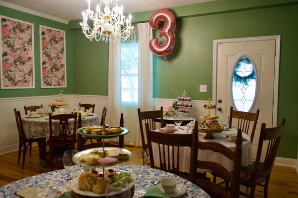 Cozy green dining room decorated for a third birthday party with floral accents.