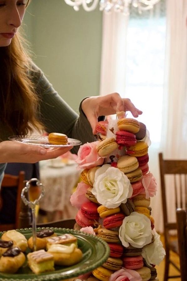 Woman picking a macaron from a colorful macaron tower decorated with flowers.