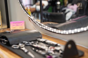 Close-up of hairdressing scissors and a business card on a salon workstation.