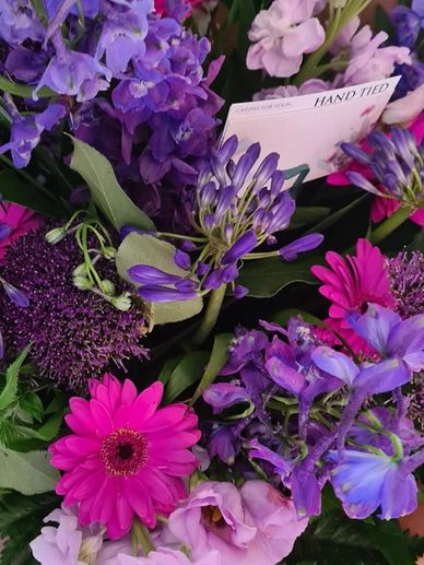 Purples pinks shocking pink, hand tied bouquet full of stocks delphinium gerbra and agapanthus