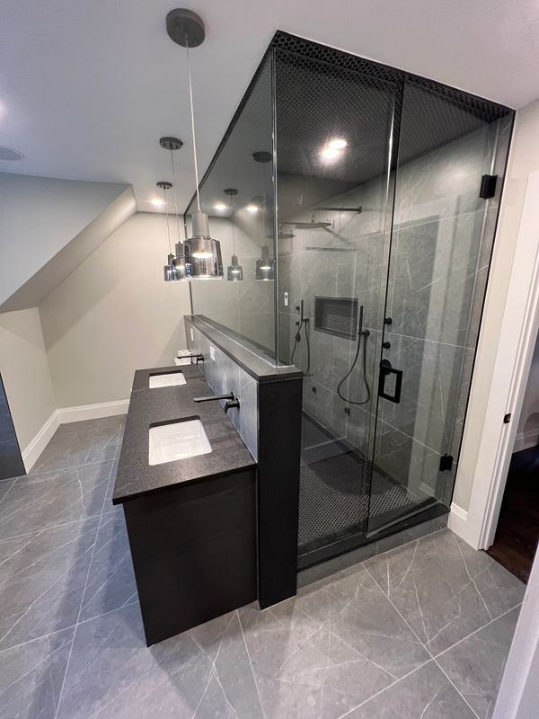 Modern bathroom with glass-enclosed shower and dual sinks.