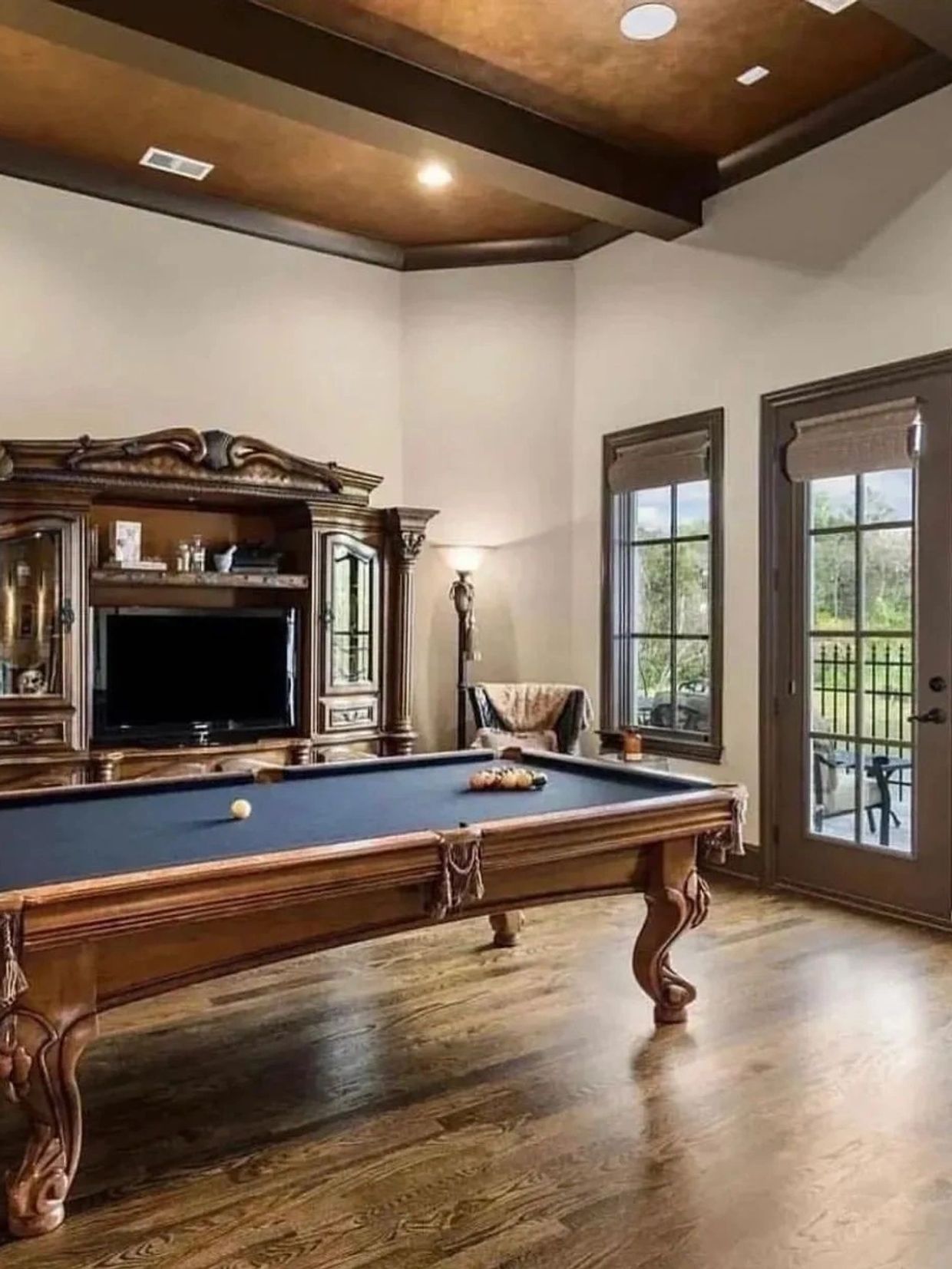Elegant game room with a classic wooden pool table and large windows.