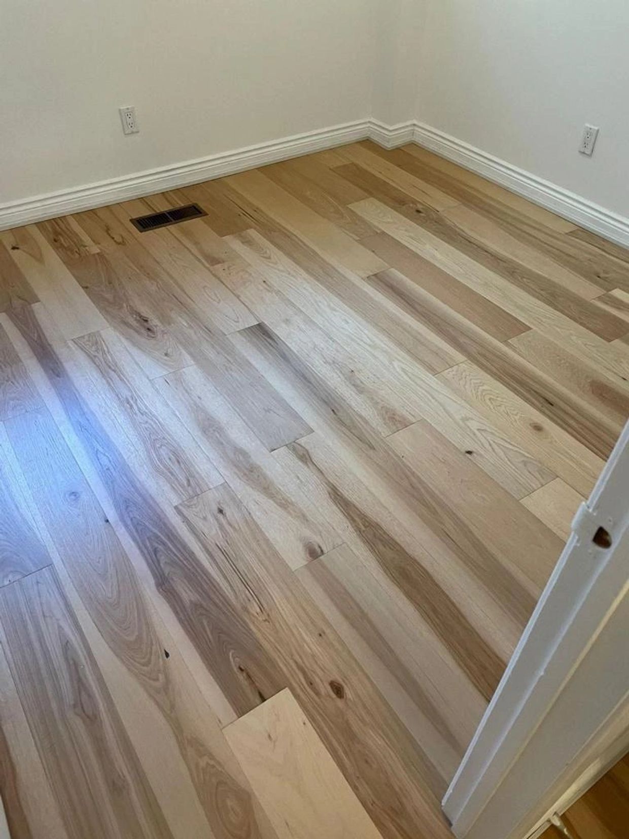 Empty room with polished wooden floors and white walls.