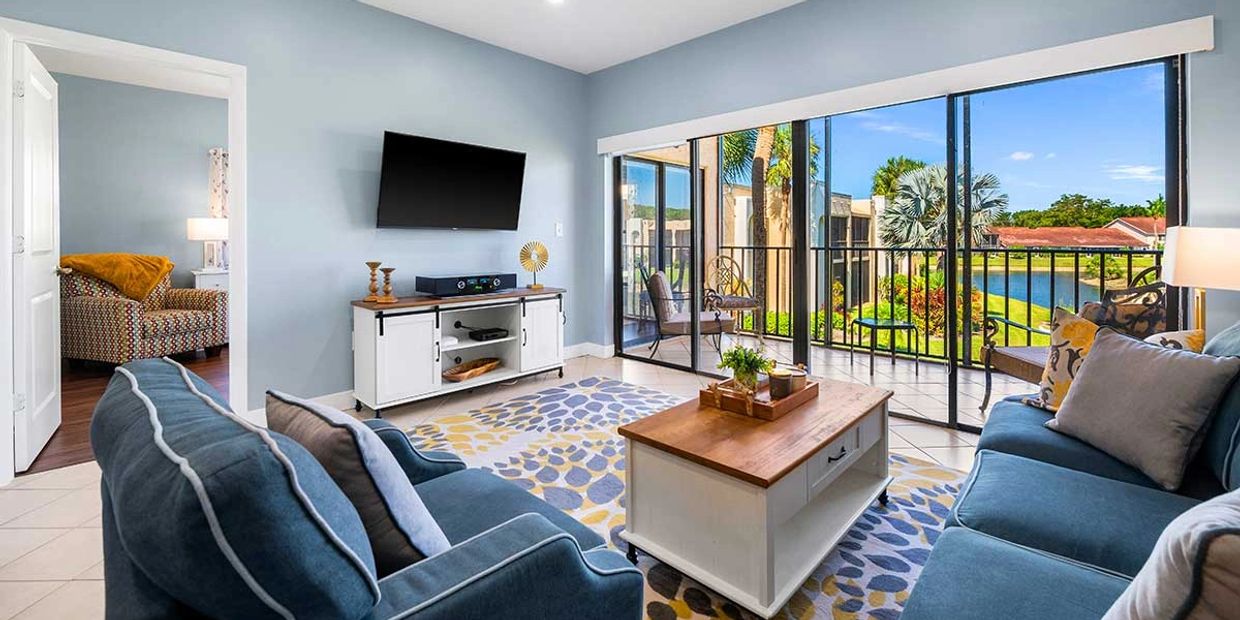 Bright living room with blue sofas and a scenic balcony view.