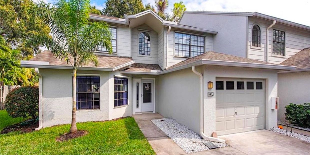 Two-story house with a garage and palm tree in front yard.