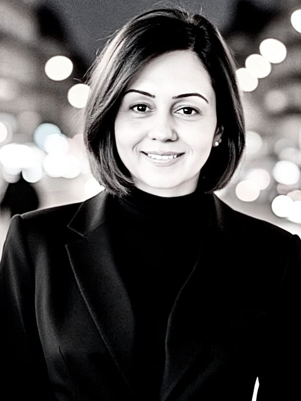 Woman in black coat smiling in black and white photo.