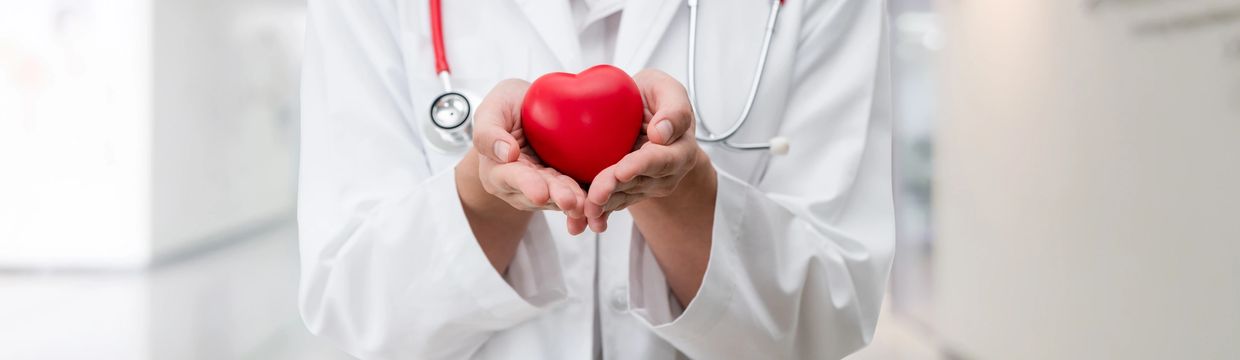 Doctor holding a red heart symbolizing care and heart health.