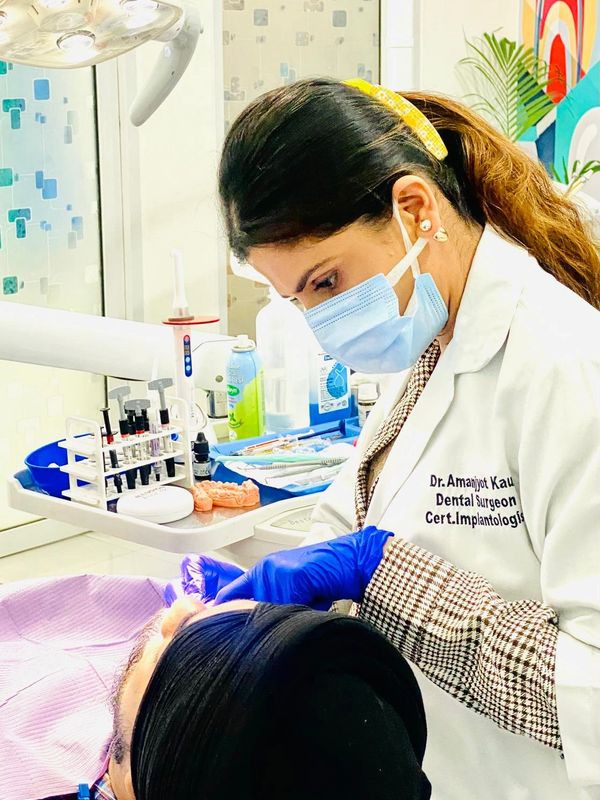 Female dentist wearing mask and gloves treating a patient in clinic.