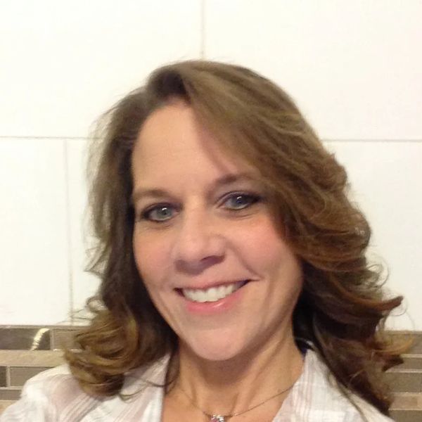 A smiling woman with wavy hair and light makeup.