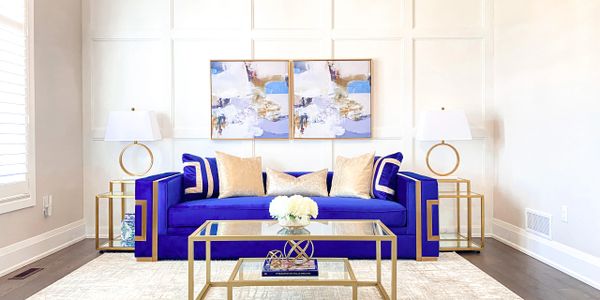 A blue sofa with cushions on it in the background with coffee table in front and side tables beside