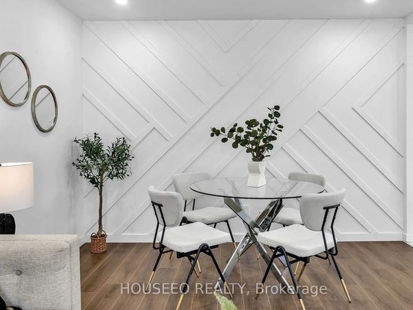 Modern dining area with glass table and white chairs on wooden floor.