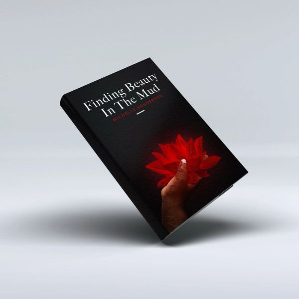 Book titled 'Finding Beauty In The Mud' with a hand holding a red flower on the cover.
