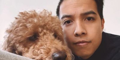Man posing with a brown fluffy dog.