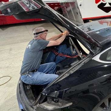 Man working inside car trunk with the lid open.