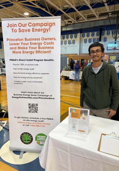 Person standing next to an energy-saving campaign booth in a gym.