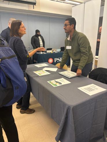 Two people talking over a table at an event.