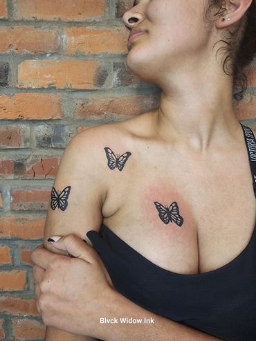 Black butterfly tattoos on a woman's shoulder and chest.