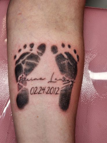 Tattoo of baby footprints with name and birth date.