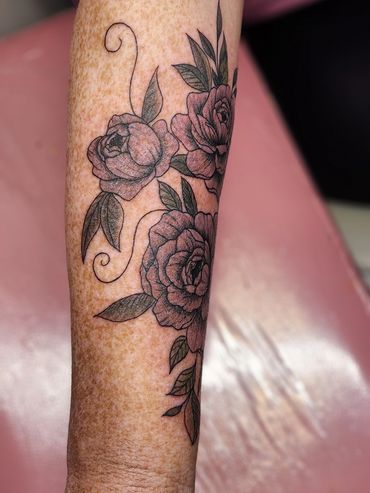 Floral tattoo with roses and leaves on arm.