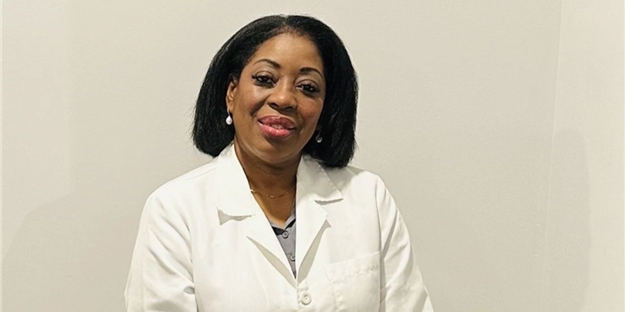 Smiling woman in a white lab coat against a plain background.