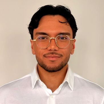 Portrait of a man wearing glasses and a white shirt.