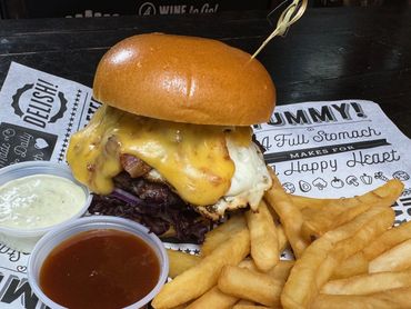 Cheeseburger with fries and two dipping sauces on a rustic table.