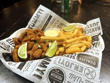 Fried seafood and crispy fries served with lime wedges and dipping sauce.