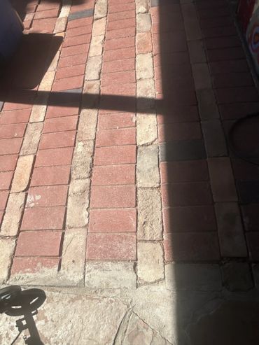 Sunlit brick and stone floor with shadows creating geometric patterns.