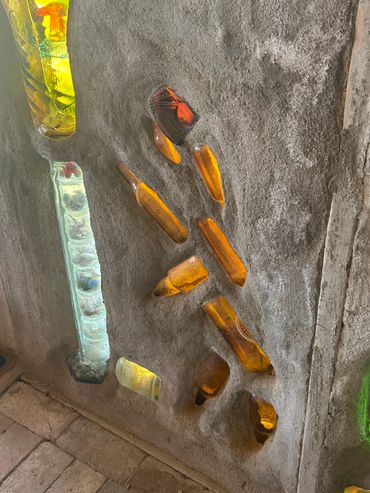 Colored glass bottles embedded in a textured concrete wall.