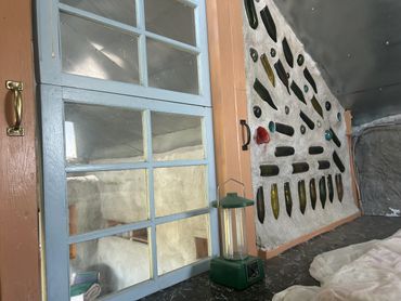 Wall decorated with embedded glass bottles and a green lantern on a black surface.