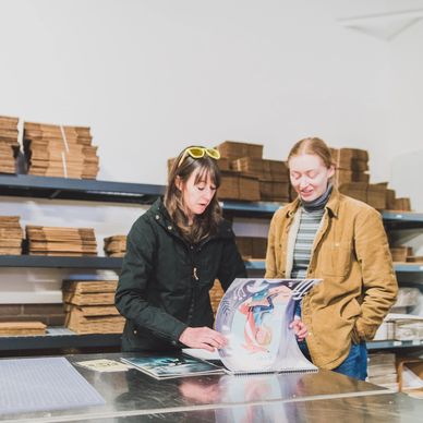 Two people standing at a table, examining and discussing a product.