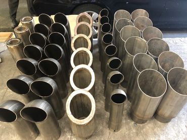 Various metal pipe sections of different shapes and sizes arranged on the floor.