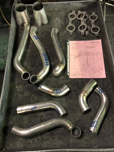 Metal pipes and clamps arranged on a tray with a document.