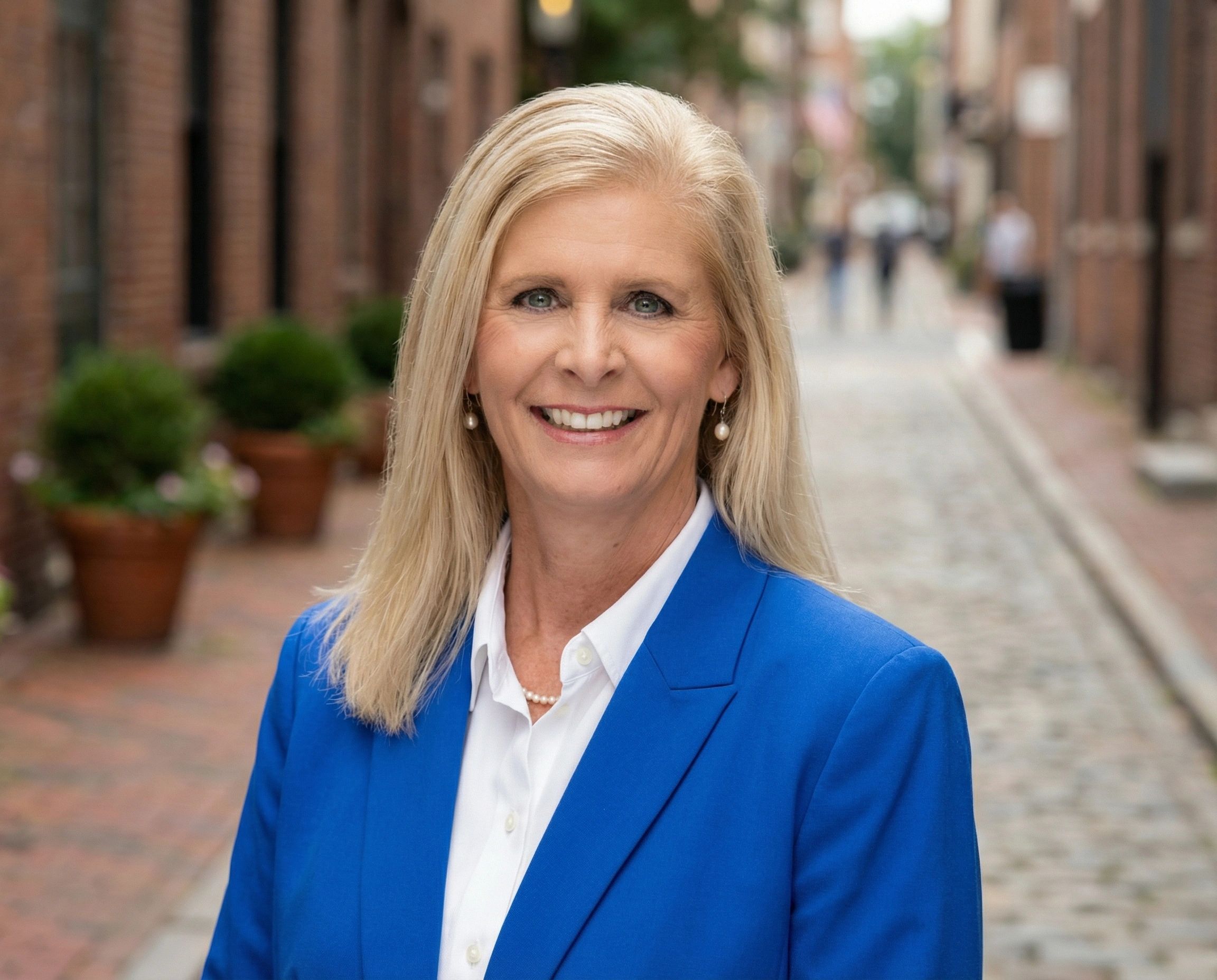 Stephanie "Lyn" Leonard in a blue blazer standing on a cobblestone street.