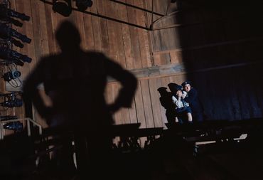 Dramatic shadow looms over two seated people in a wooden room.